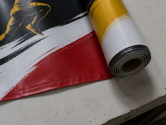 Bandera publicitaria sublimada junto al rollo de tela impresa, sobre la mesa del taller